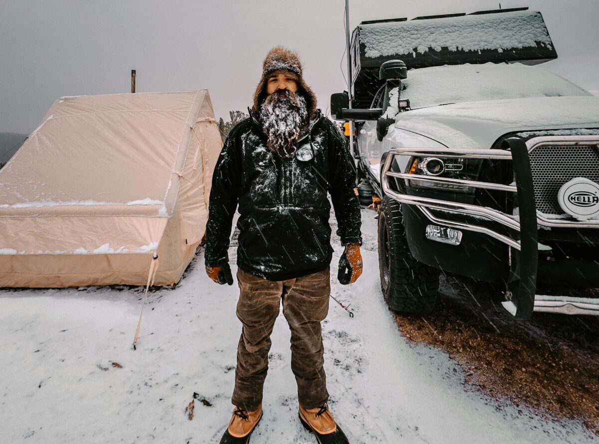 Bearded Man by Tent and Truck in Snowy Scenery